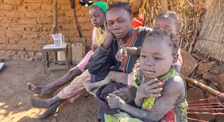 أم وأطفالها يجلسون في مأوى مؤقت في جنوب كردفان بالسودان.